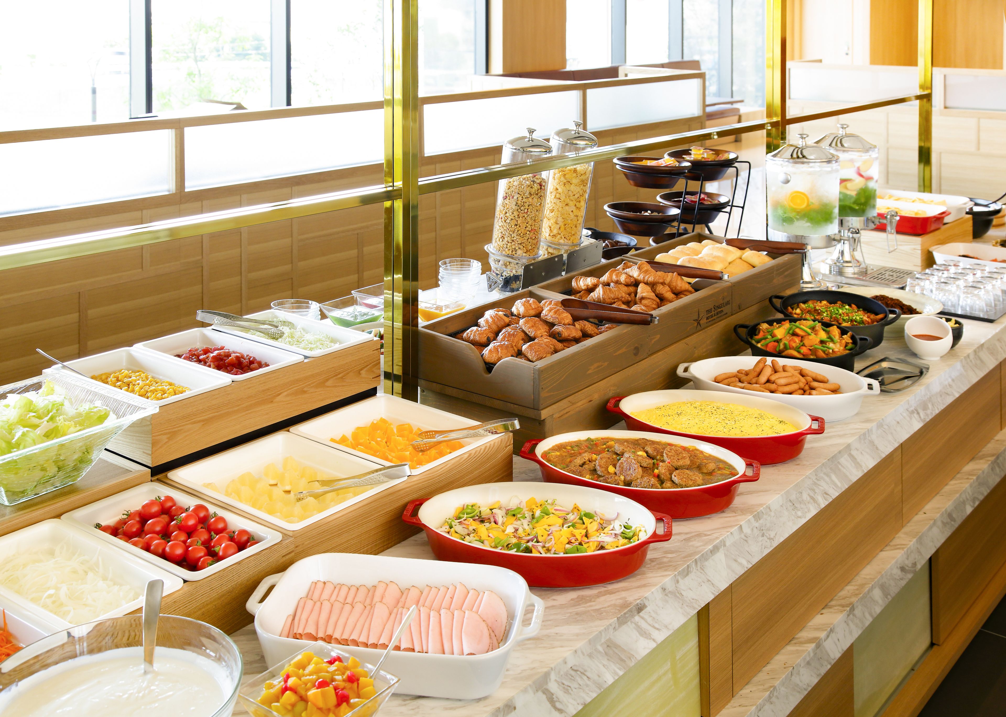 A buffet with various food items including fruits, vegetables, meats, and baked goods.
