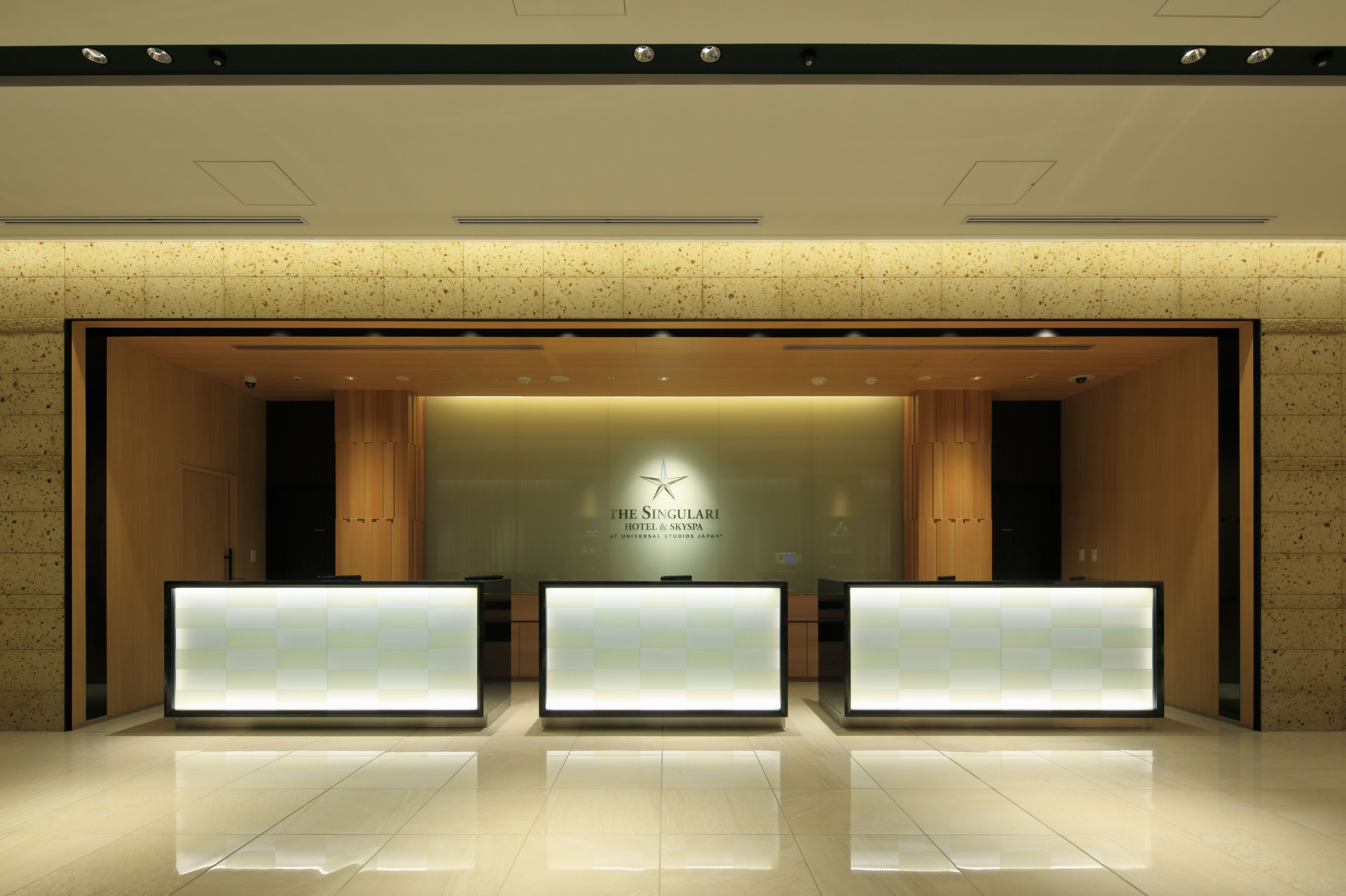 A hotel reception area with a modern design, featuring a reception desk, a logo, and a clean, tiled floor.