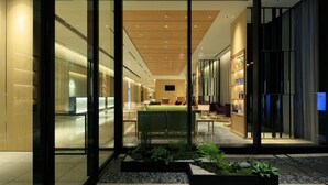 A modern hotel lobby with glass doors, a reception desk, and a seating area with a green sofa. - The Singulari Hotel & Skyspa at Universal Studios Japan (Osaka)
