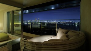 A modern bedroom with a large window overlooking a cityscape at night. - The Singulari Hotel & Skyspa at Universal Studios Japan (Osaka)