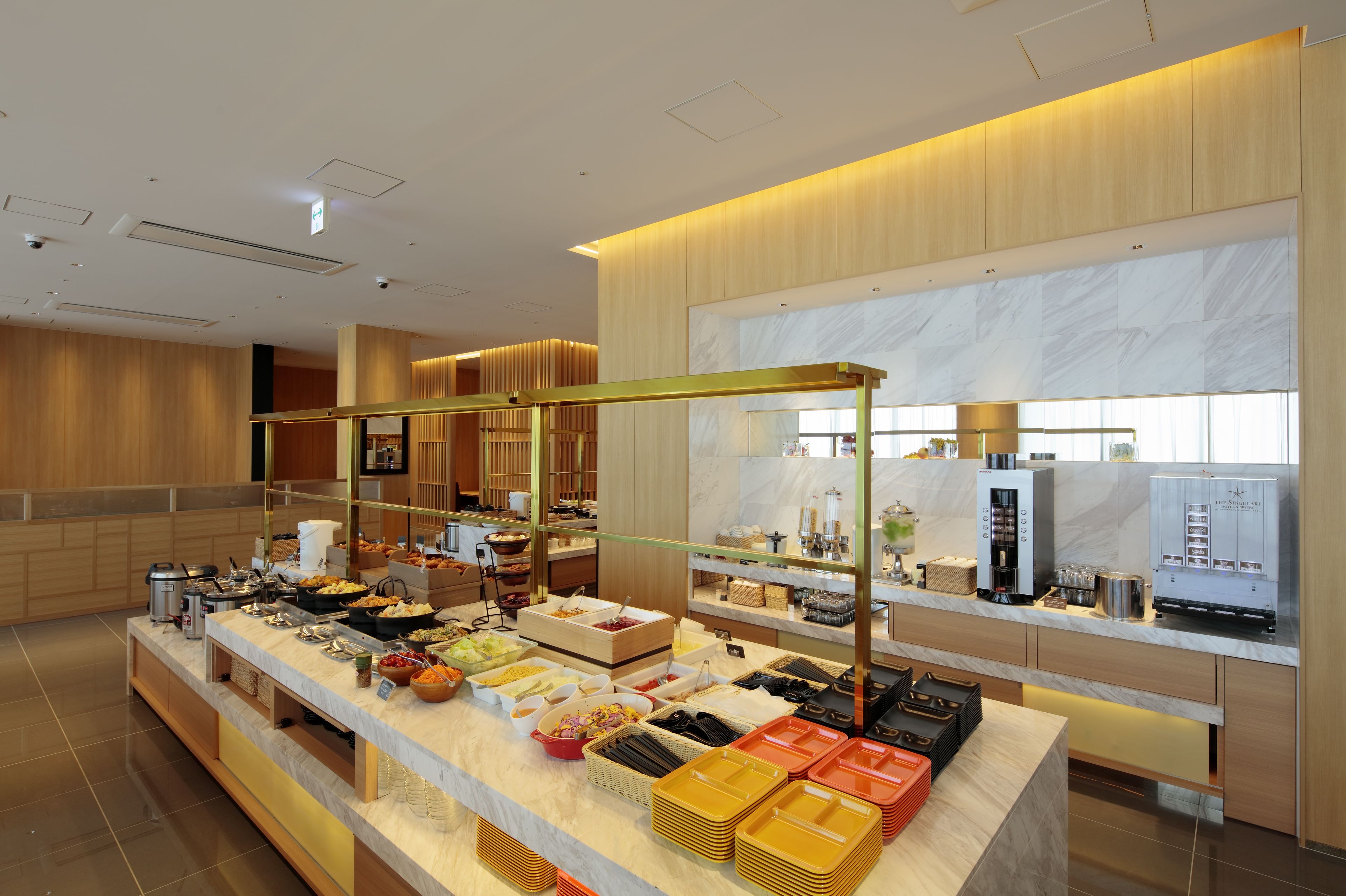 Un espace buffet avec différents stands de nourriture et une machine à café.