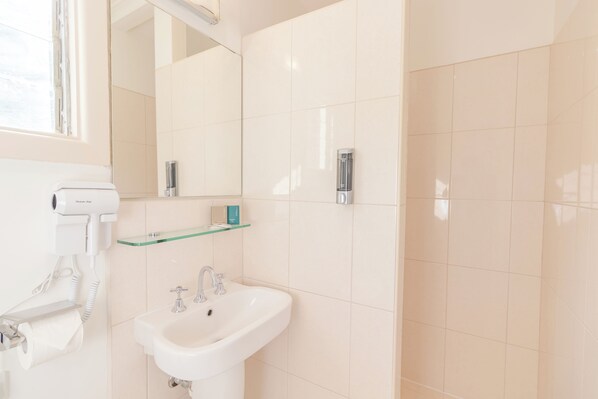 A bathroom with a white sink, a glass shelf, a mirror, and a hairdryer. - Warburton Lodge (Warburton)