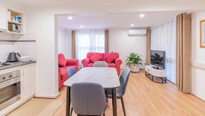 A modern living room with a dining table, red sofa, and a TV. - Warburton Lodge (Warburton)