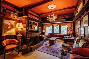 A cozy, wood-paneled room with a fireplace, plush seating, and bookshelves. - Warburton Lodge (Warburton)