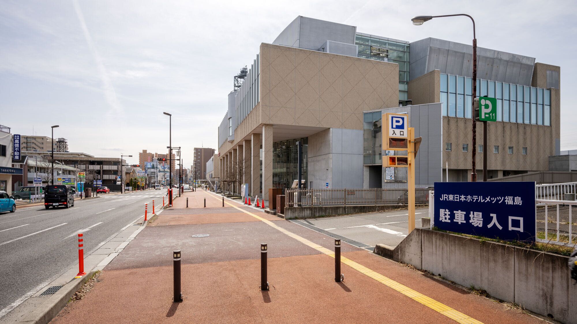 Um edifício moderno com placa de estacionamento, faixa de pedestres e estrada desimpedida.