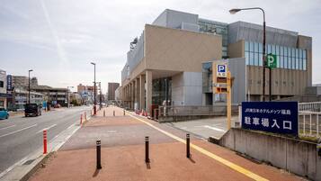 Um edifício moderno com placa de estacionamento, faixa de pedestres e estrada desimpedida.