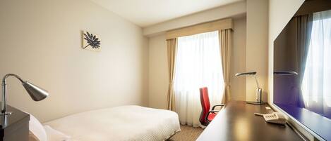 A hotel room with a bed, a desk with a computer, a telephone, and a TV.