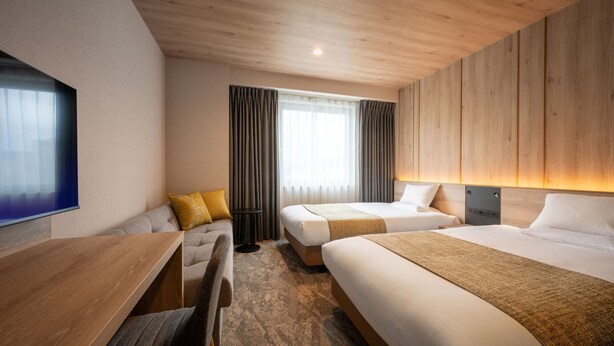 A hotel room with two beds, a wooden desk, a chair, a TV, and a window with curtains. - JR East Hotel Mets Fukushima (Fukushima)