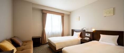 Habitación de hotel con dos camas, un sofá, una mesita de noche con lámpara y una ventana con cortinas.