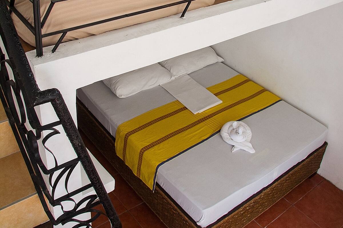 Una cama litera con dos niveles, cada uno con un colchón y almohadas.