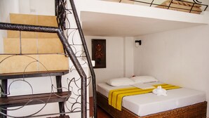 Une chambre à coucher avec un lit, un escalier en bois et un luminaire fixé au mur.