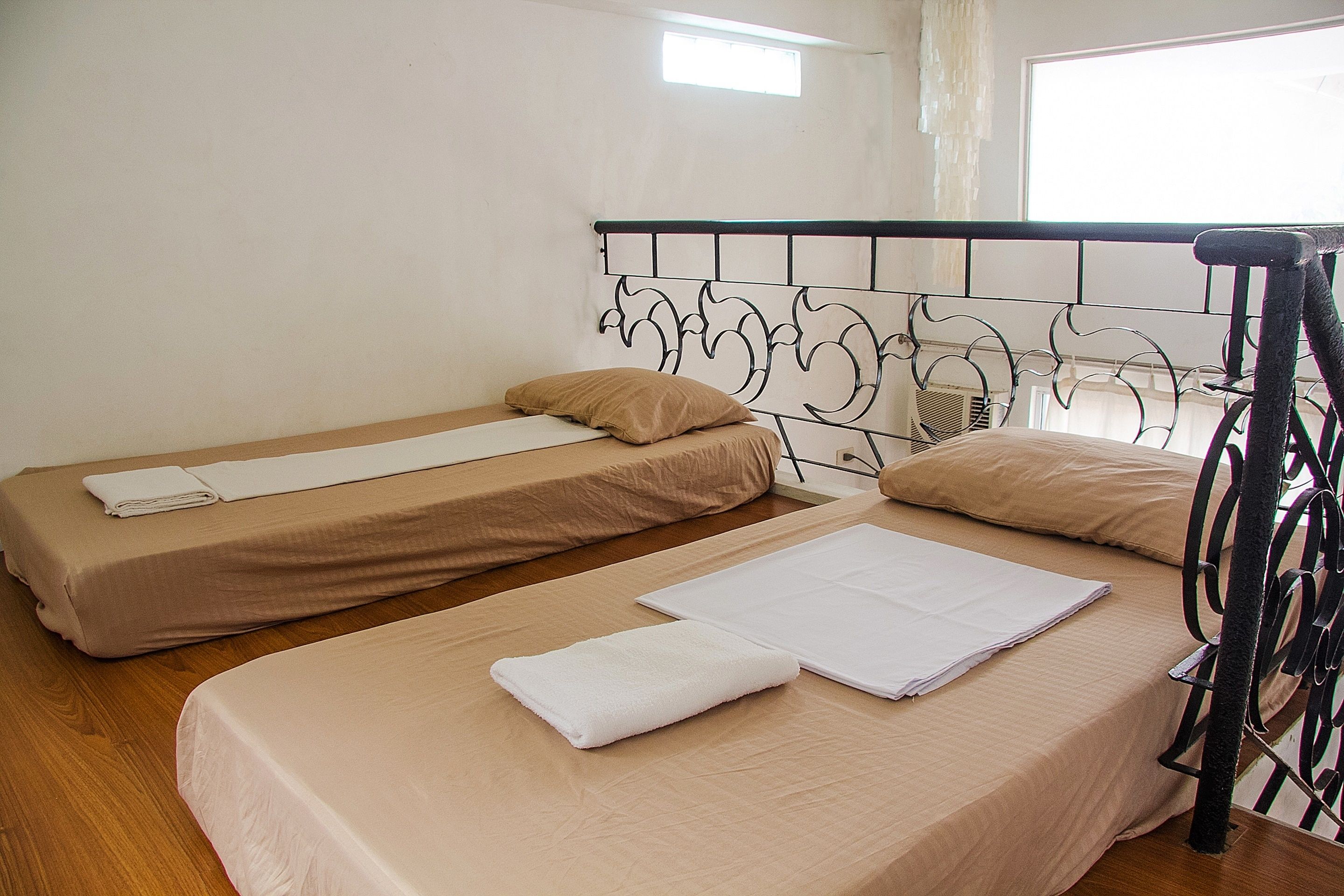 A room with two single beds, a window, and a cat tree.