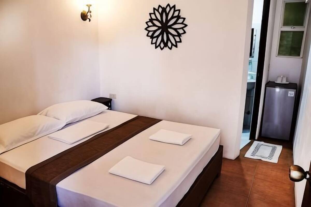 Habitación de hotel con una cama, un adorno en la pared y una pequeña kitchenette.