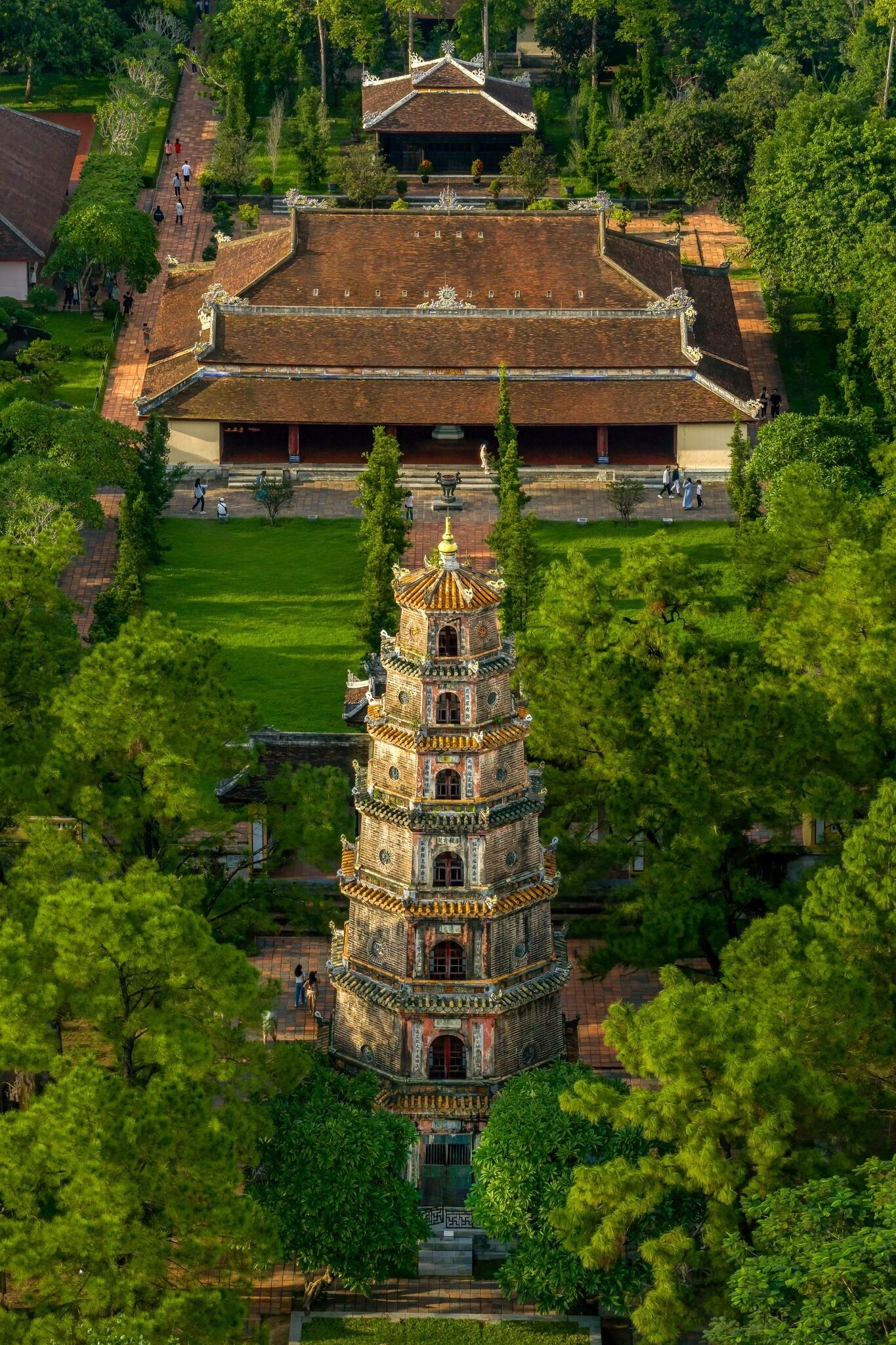 A traditional pagoda with a multi-tiered roof and ornate decorations, surrounded by lush greenery and a well-maintained courtyard.