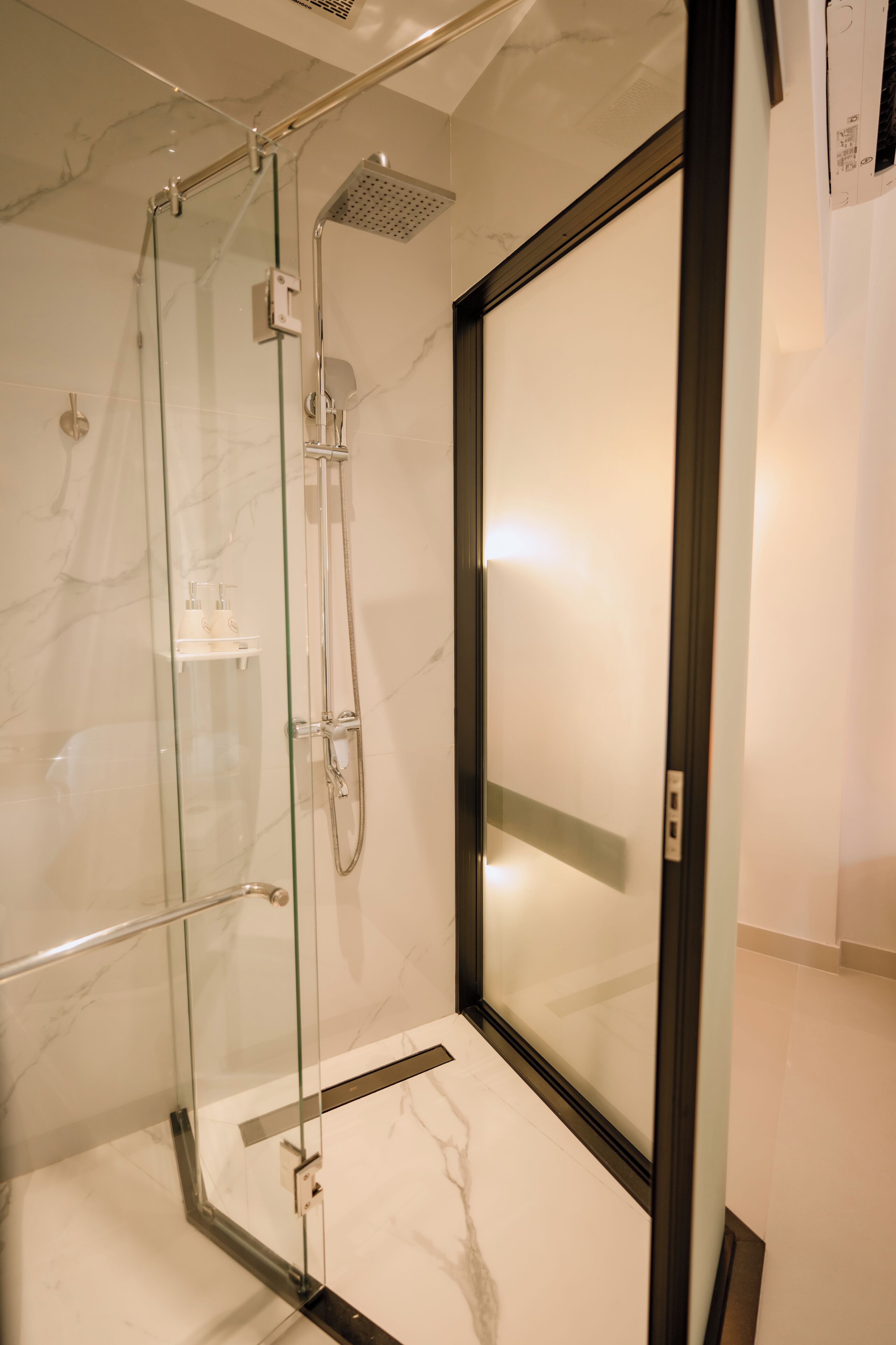Une douche entièrementClose avec des parois en verre, un sol en marbre et un design moderne.