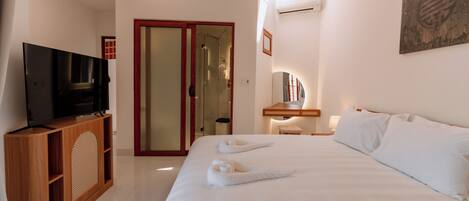 A hotel room with a bed, a TV, a desk, and a wardrobe.