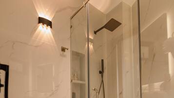 Un baño moderno con ducha envuelta en vidrio, inodoro blanco y pared revestida de mármol.