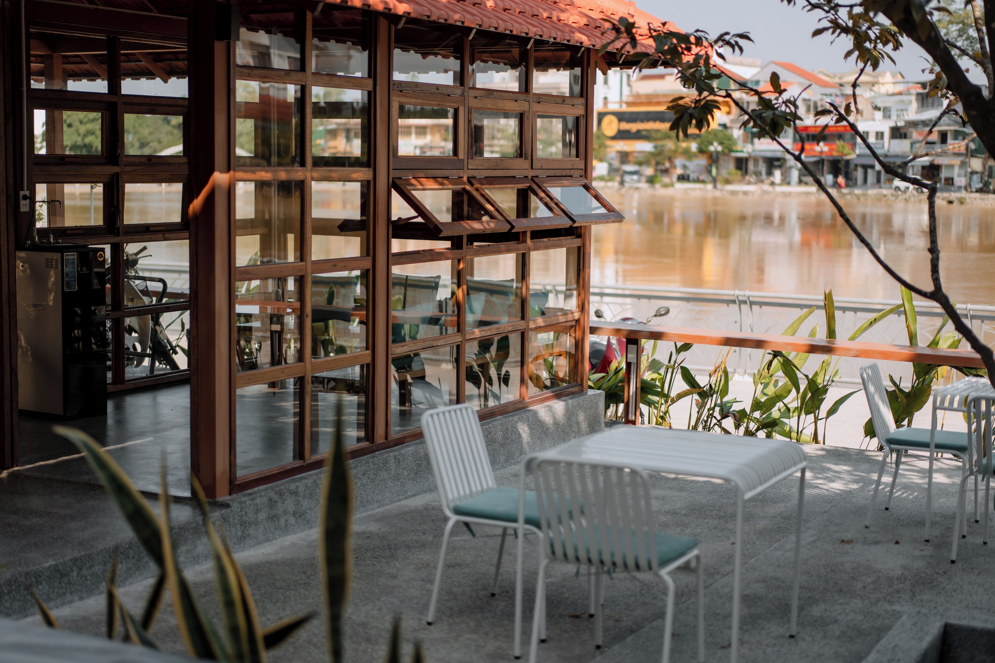 A terrace with a table and chairs, overlooking a body of water and a cityscape.