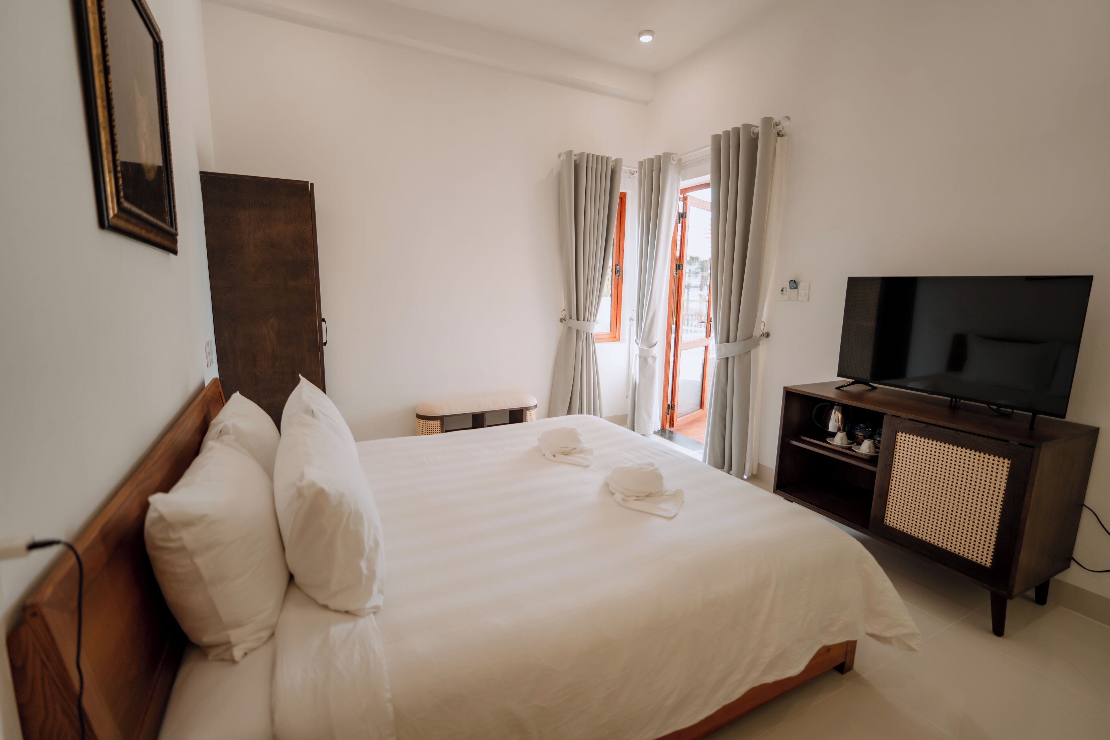 A hotel room with a large bed, a television, and a small table.