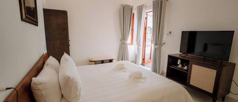 A hotel room with a large bed, a television, and a small table.