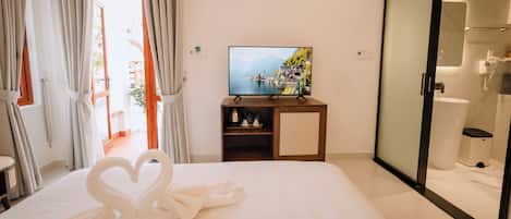 A hotel room with a bed, a TV displaying a scenic view, a wardrobe, and a bathroom.