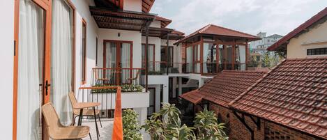 Un edificio residencial con balcón, mobiliario exterior y un pequeño jardín.