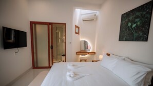 A hotel room with a large bed, a flat-screen TV mounted on the wall, a bathroom with a glass door, and a painting on the wall. - Hue Riverside Villa (Hue)