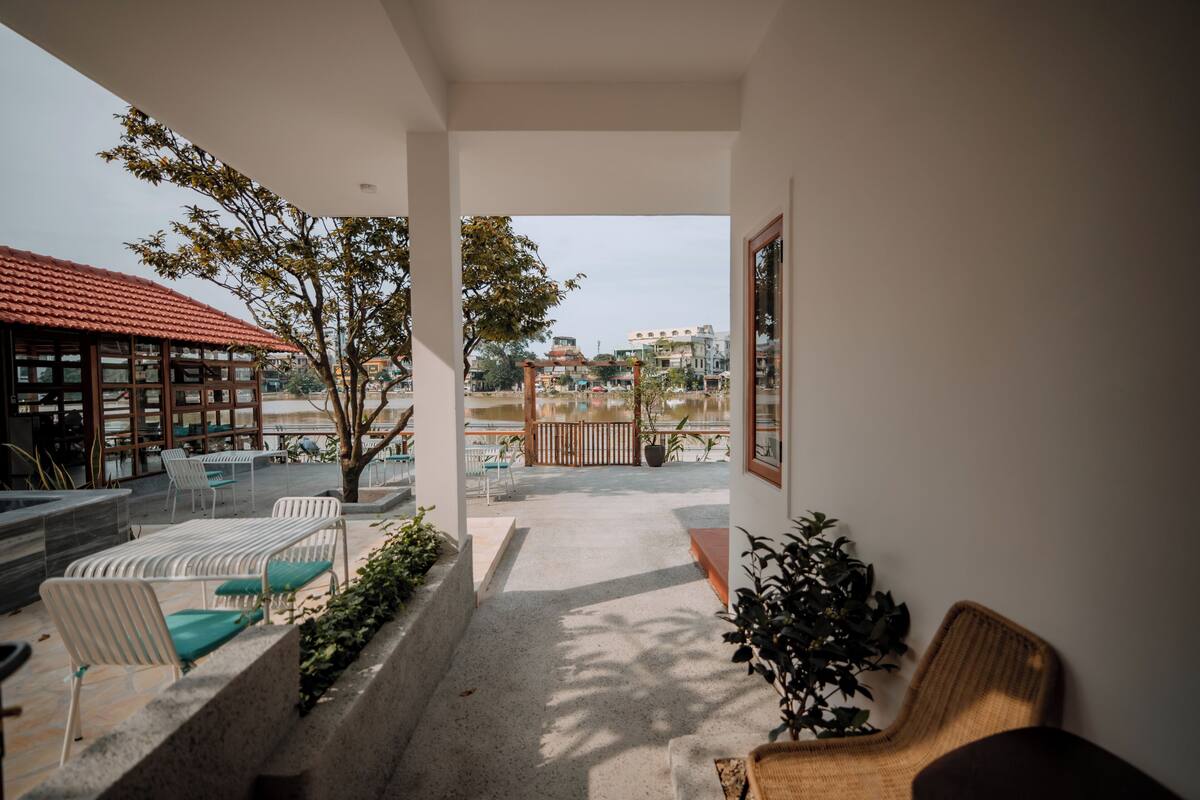 Uma varanda com área de estar externa, vista da cidade e um edifício com telhado vermelho.