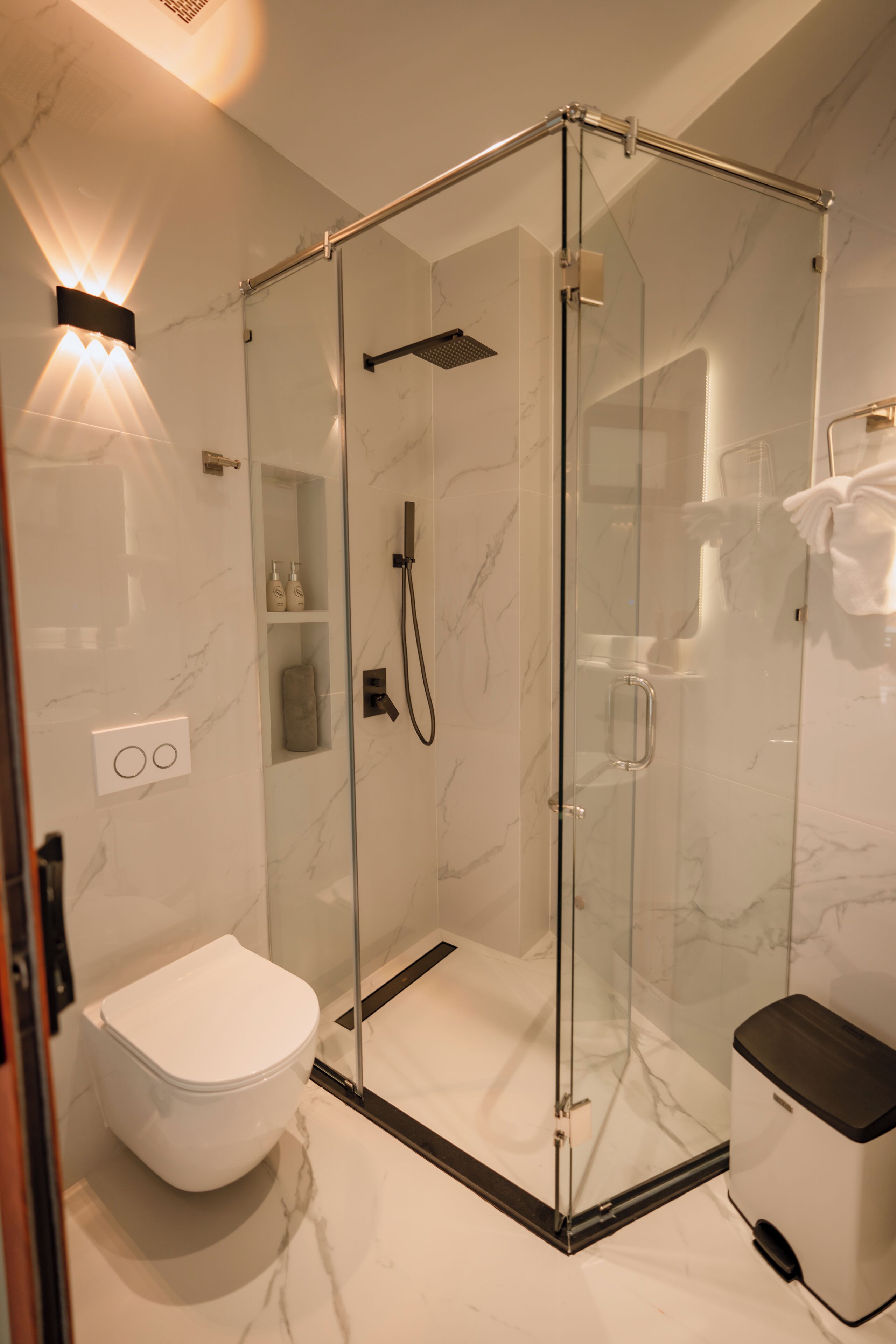 Un baño moderno con ducha envuelta en vidrio, inodoro blanco y bidé.