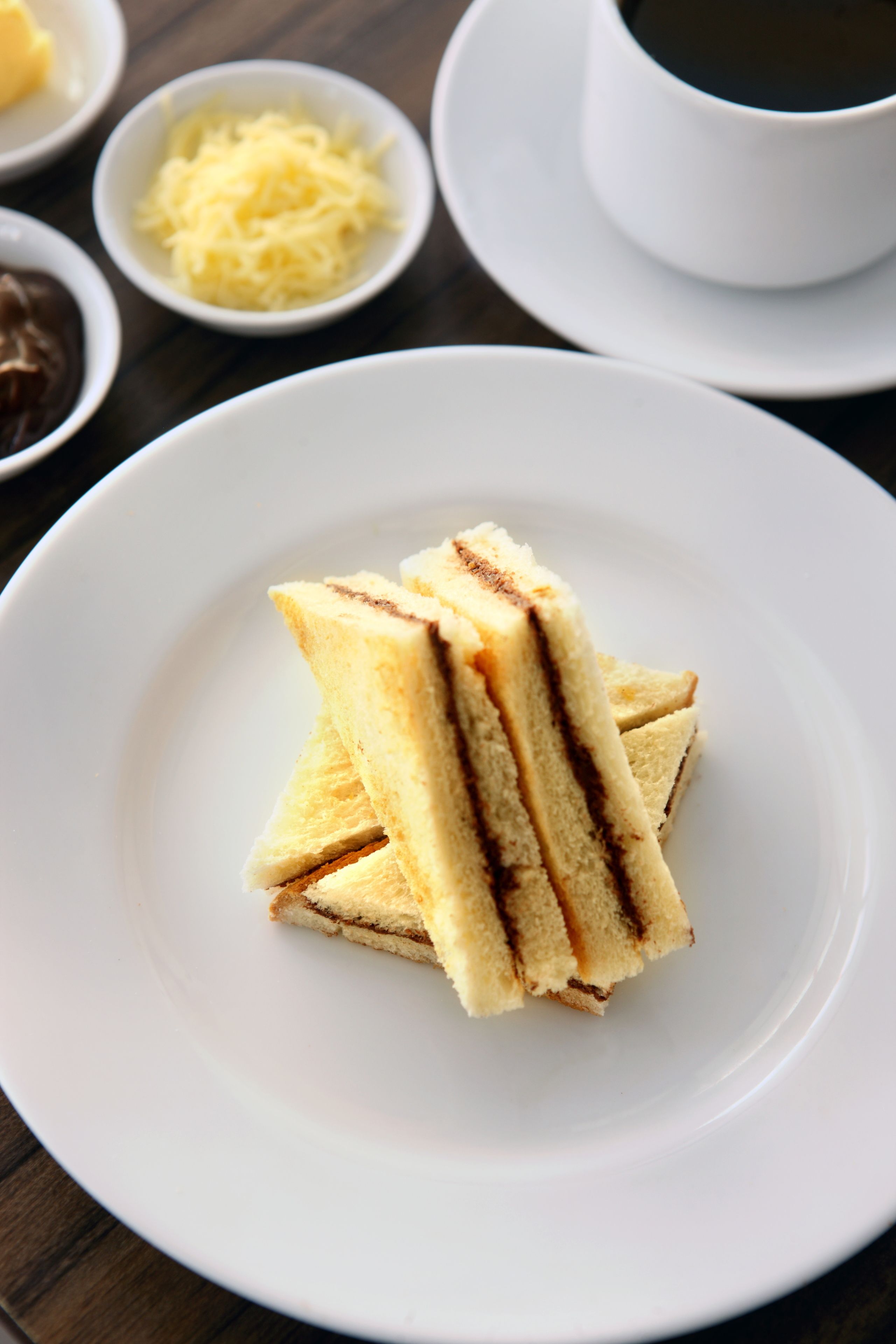 A white plate with a sandwich on a wooden table.