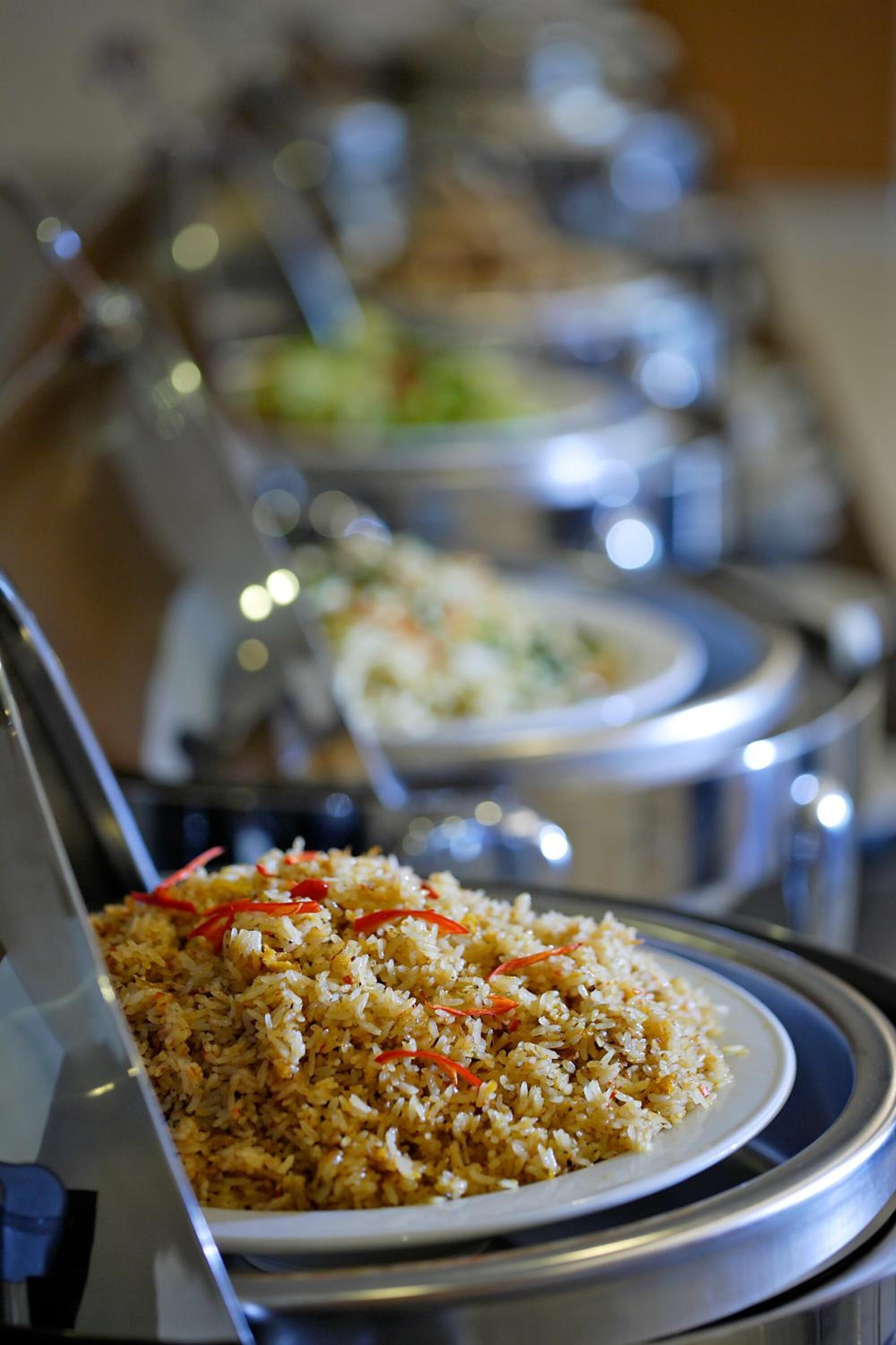 A buffet with various dishes, including a plate of fried rice garnished with red peppers.