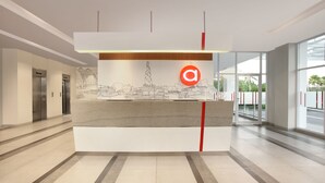 A reception desk with a cityscape mural, elevators, and a glass entrance. - Amaris Hotel Padang (Padang)
