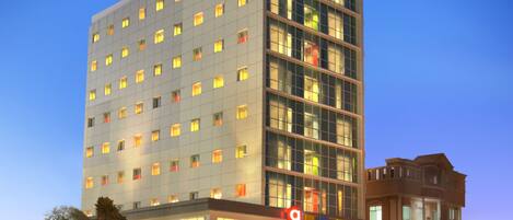 Un hotel de varios pisos con un diseño moderno, que presenta un llamativo letrero de 'Amaris Hotel' en la parte superior.