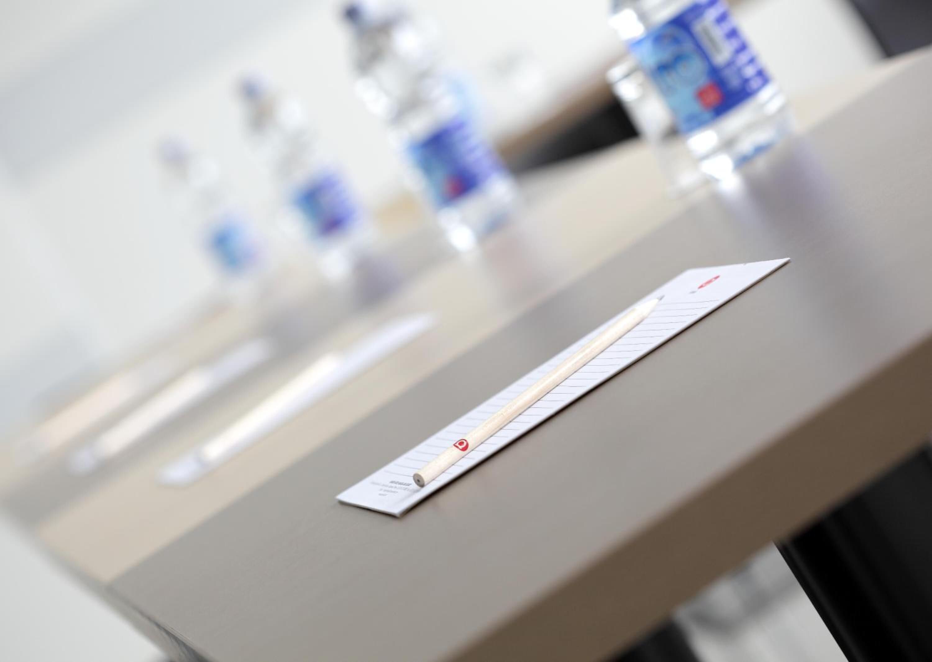 Un comptoir d’accueil d’hôtel avec un bloc-notes et un stylo, et un arrière-plan flou avec des bouteilles d’eau.