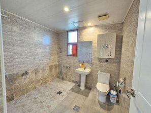 A bathroom with a shower, toilet, sink, and a cabinet.