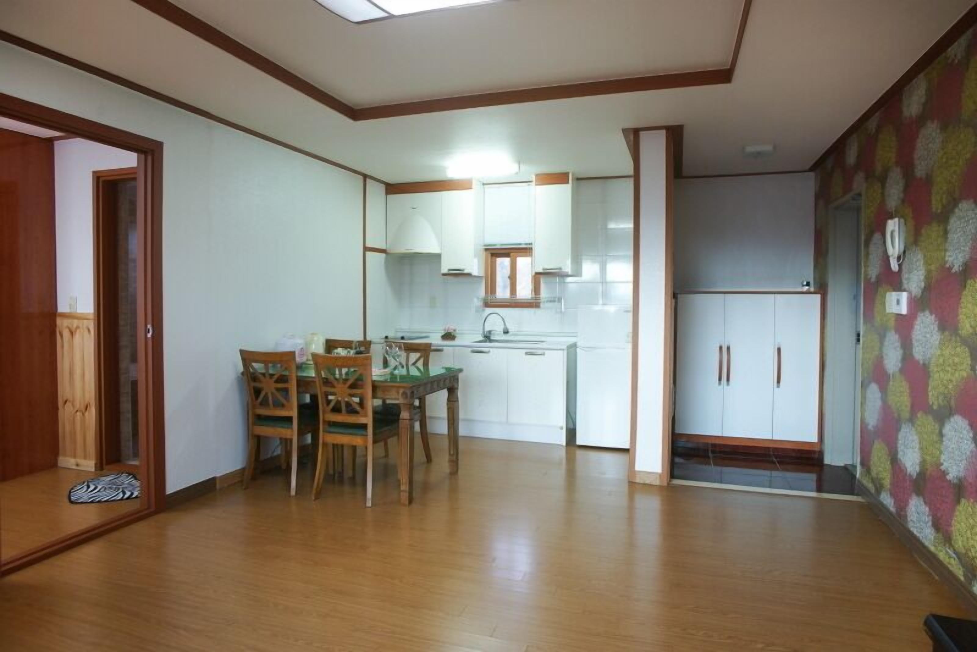 Une cuisine compacte avec un coin repas, un plancher en bois et un mur décoré de motifs.