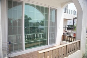 A balcony with a wooden railing and a view of a residential area. - Olleh House (Seogwipo)