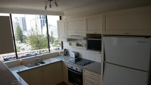 A modern kitchen with white cabinets, a stainless steel oven, a microwave, and a refrigerator.