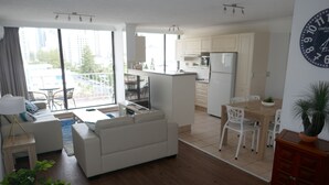 A modern apartment with a living room, dining area, and kitchen. It features a large window, a sofa, a dining table, and a kitchen counter.