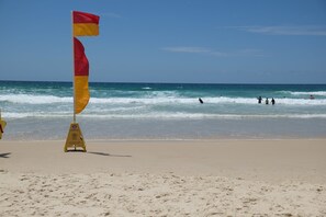 A beach with a lifeguard flag and a warning sign.