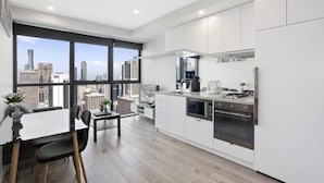 Una cocina moderna con armarios blancos, una estufa de acero inoxidable y un amplio ventanal con vistas a la ciudad.