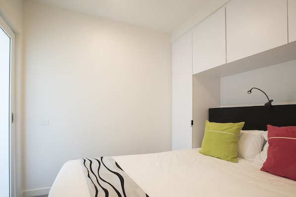 A bedroom with a bed, white walls, and a black headboard.