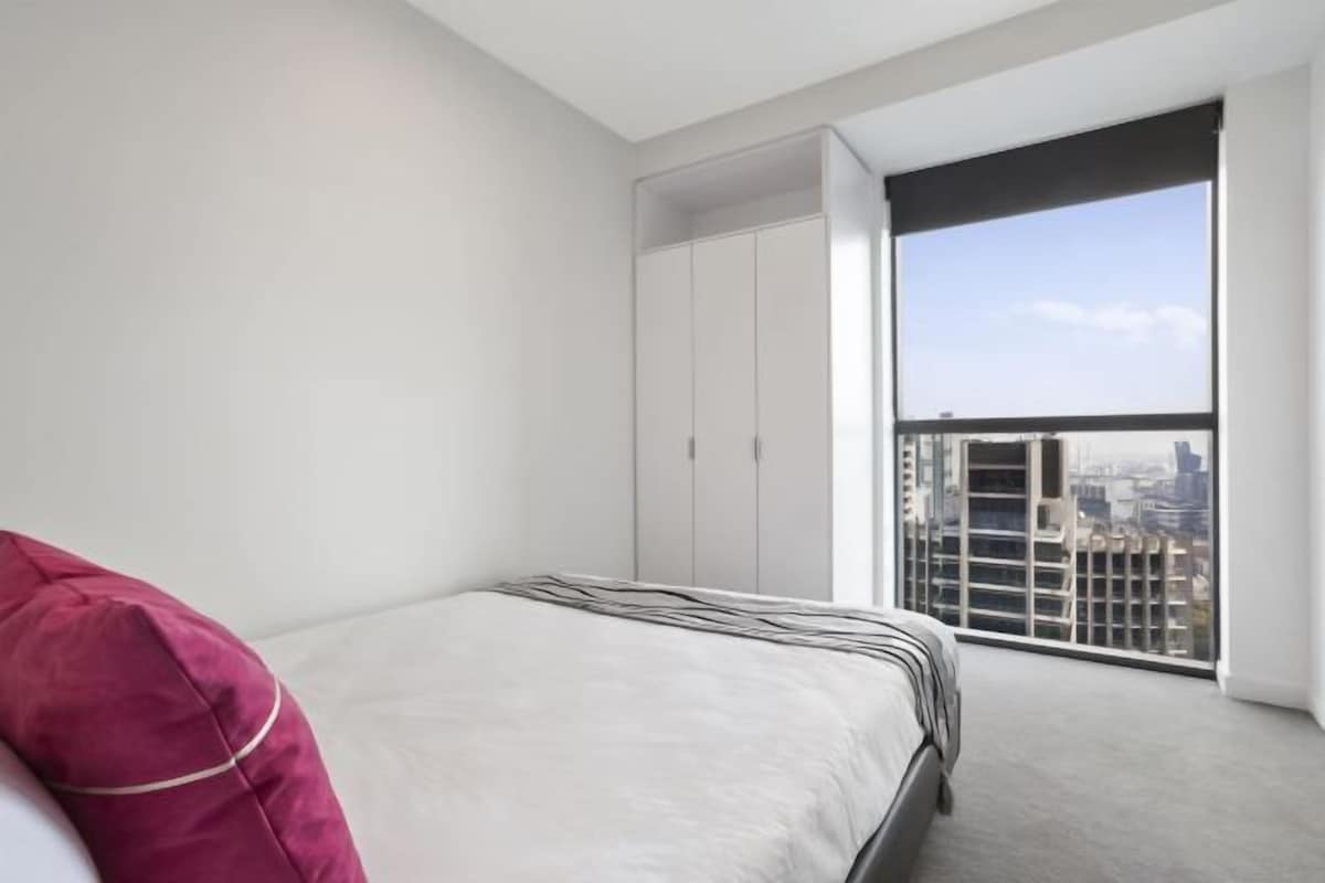 Un dormitorio moderno con una cama grande, un armario y un balcón con vistas a la ciudad.