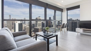 Una sala de estar moderna con ventanas amplias, un sofá, una mesa de centro y un televisor.