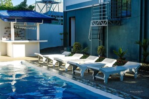 A swimming pool with lounge chairs and a bar area.