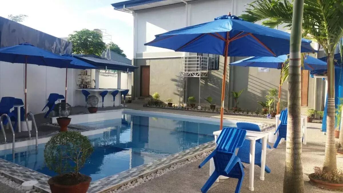 A pool area with blue umbrellas, chairs, and potted plants.