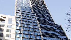 Un edificio alto y moderno con fachada de vidrio y una estructura vertical destacada.