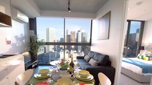Una sala moderna con comedor, ventanas amplias con vista a la ciudad, un sofá y una cama.