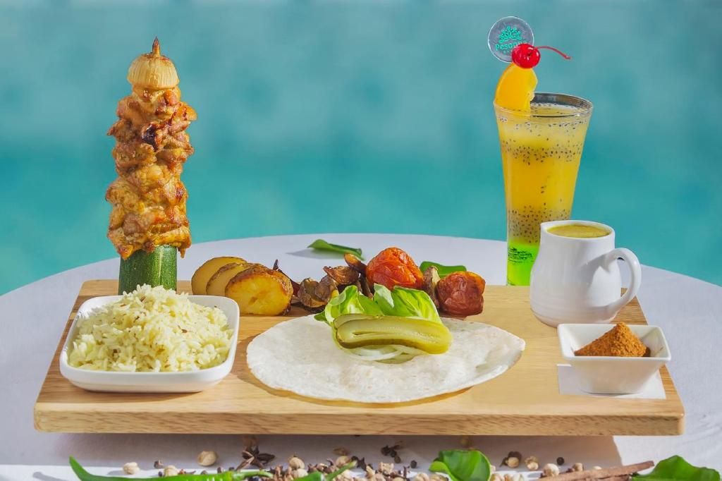 A meal setup with grilled meat, vegetables, rice, and a beverage.