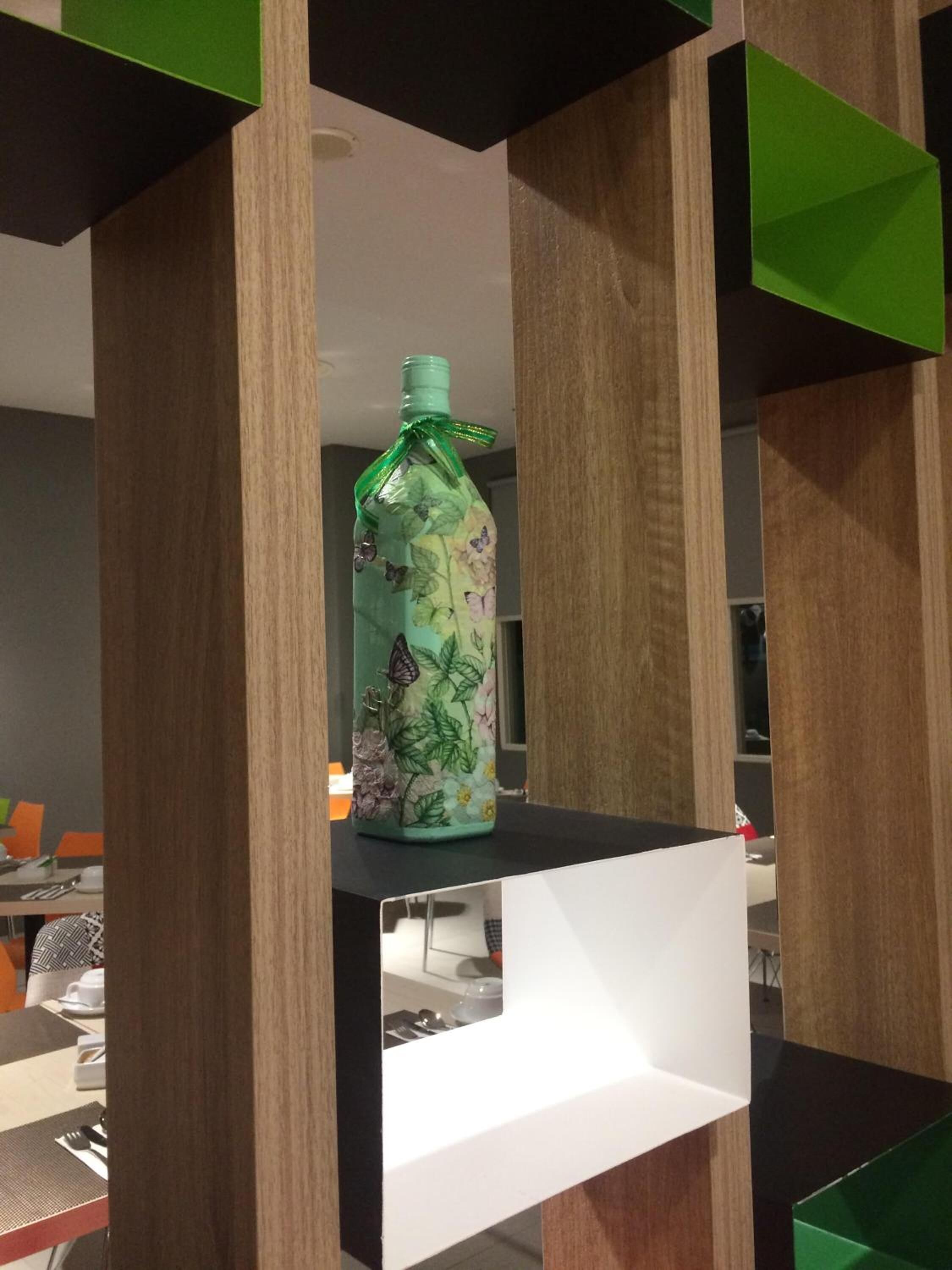 A bottle with a floral design on a white shelf in a modern room with wooden accents.